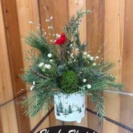 Holiday evergreen arrangement in a white container with a red bird ornament