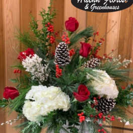 Holiday floral arrangement with red roses, white blooms, pinecones, and berries
