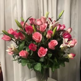 Pink roses and lilies arranged in a clear glass vase
