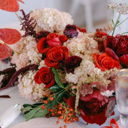 Red roses and pale hydrangeas arranged with anthuriums on a table