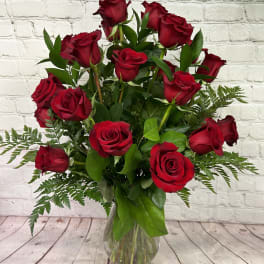 Tall arrangement of long-stemmed red roses in a clear glass vase