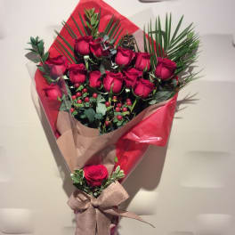 Bouquet of red roses wrapped in red and tan paper with a ribbon