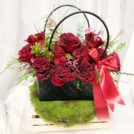 Red roses in a black basket with a pink ribbon