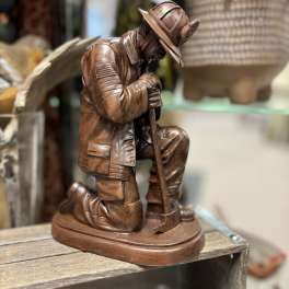 Wooden kneeling firefighter figurine holding an axe
