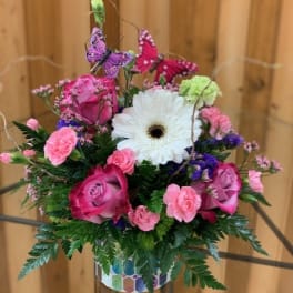 Pink roses and carnations with a white gerbera daisy in a patterned vase