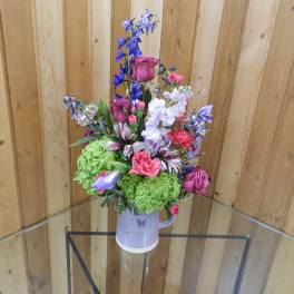 Mixed bouquet in a lavender pitcher vase with pink, purple, and green blooms