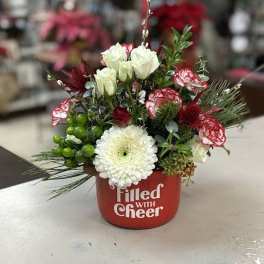 Mixed floral arrangement in a red container with white and red blooms
