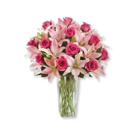 Pink roses and lilies arranged in a clear glass vase