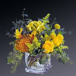 Yellow floral arrangement in a clear square glass vase
