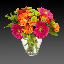 Bouquet of orange roses and pink gerbera daisies in a clear glass vase