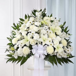 White floral spray with a ribbon on a stand