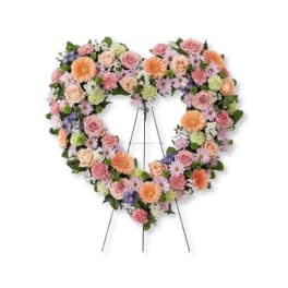 Heart-shaped floral wreath on a stand with pastel roses and daisies