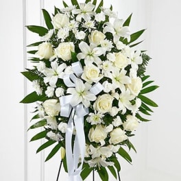 White floral standing spray with roses and lilies on an easel