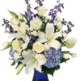 White lilies and roses with purple flowers in a blue vase