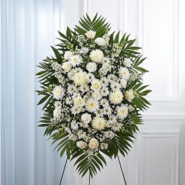 White floral standing spray with palm fronds on an easel