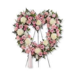 Heart-shaped floral wreath with pink and white flowers on a stand