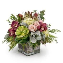 Mixed bouquet with roses, orchids, hydrangea, and greenery in a glass cube vase