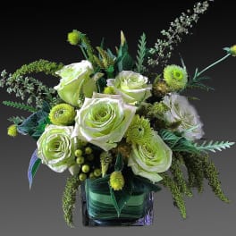 Green and white rose arrangement in a square glass vase