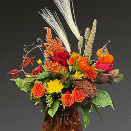 Autumn bouquet of orange and yellow flowers in an amber glass vase