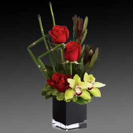 Red roses and pale green orchids in a black square vase