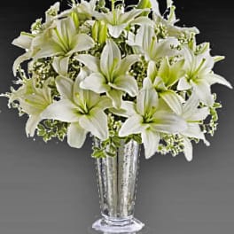 White lilies arranged in a tall glass vase