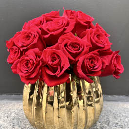 Red roses arranged in a gold ribbed vase