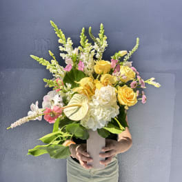 Mixed bouquet of yellow, white, and pink flowers in a tall vase