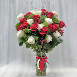 Red and white roses in a glass vase with a red ribbon