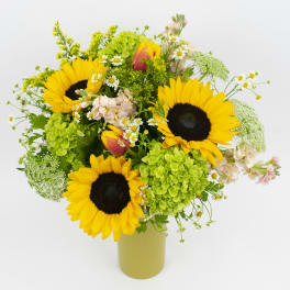 Sunflower bouquet with green hydrangeas and small white flowers in a vase
