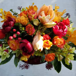 Bright mixed bouquet with orange, red, and yellow flowers in a low container