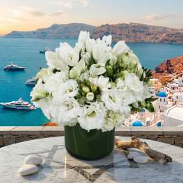 White floral arrangement in a dark green vase on a marble table
