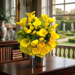 Yellow calla lilies and roses arranged in a silver vase
