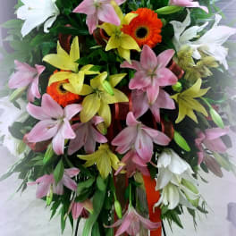 Tall standing spray of lilies and gerbera daisies in pink, white, and yellow