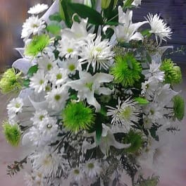 White and green funeral spray with lilies and daisies on a stand