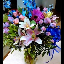Bouquet of lilies, roses, and a purple gerbera daisy in a glass vase