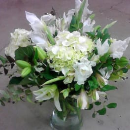 White lilies and hydrangeas arranged in a clear glass vase