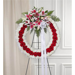 Standing funeral wreath with red roses, white flowers, and pink lilies
