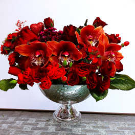 Red floral arrangement in a glass pedestal bowl