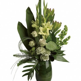 Green floral arrangement in a dark glass vase with white blooms