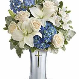 White lilies, cream roses, and blue hydrangeas in a silver vase