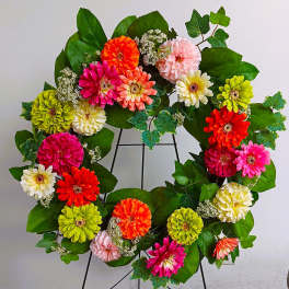 Colorful flower wreath with zinnias on a black stand