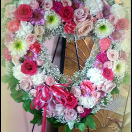 Heart-shaped floral wreath with pink and white roses on an easel