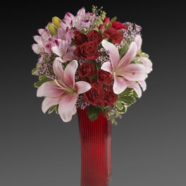 Bouquet of red roses and pink lilies in a tall red vase