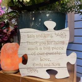 Puzzle-shaped thank-you sign beside flowers and a salt lamp