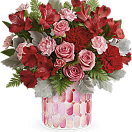 Pink and red floral arrangement in a patterned glass vase