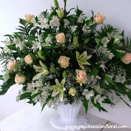 White and peach floral arrangement in a white pedestal vase