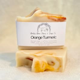 Two orange turmeric soap bars stacked on a soft surface