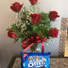 Red roses in a glass vase with a red ribbon and a birthday Oreo cookie package