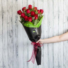Bouquet of red roses wrapped in black paper with a pink ribbon