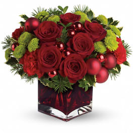 Red roses and carnations in a square glass vase with holiday ornaments